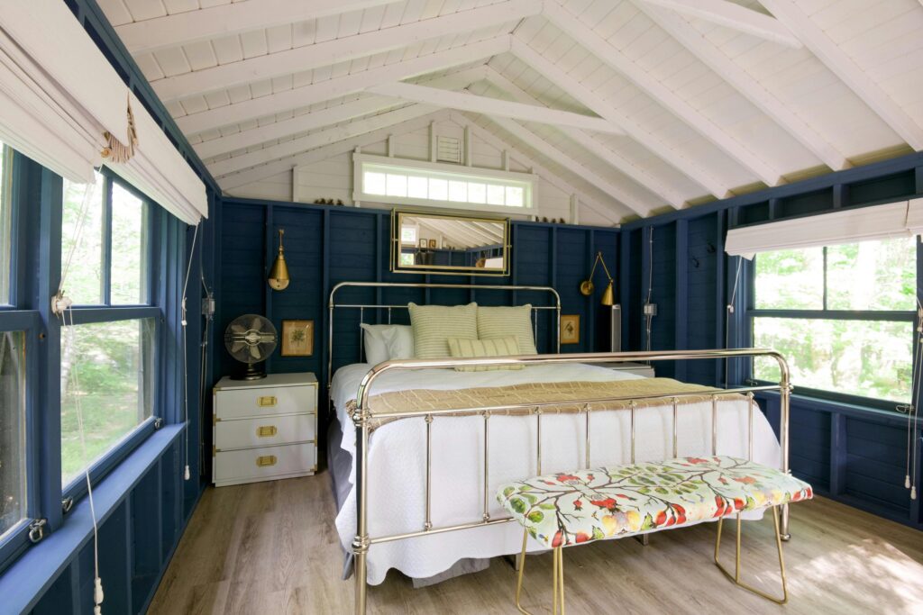 Coastal blue and white bedroom with brass bed and campaign style furniture.