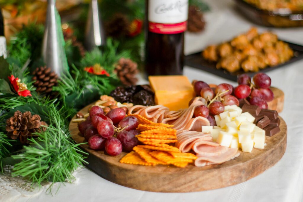 Wood charcuterie board with meat and cheese next to a bottle of wine