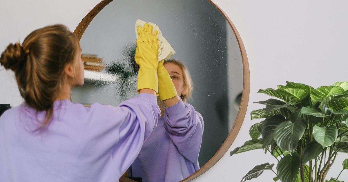 Woman cleaning a mirror