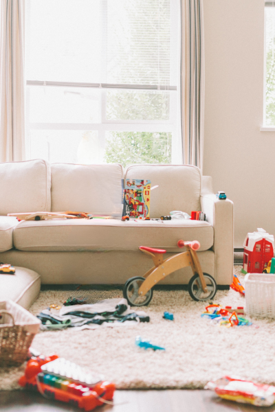 A cozy living room scattered with colorful toys and a wooden scooter.