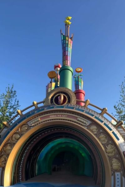 Colorful tunnel entrance with cartoon-style decorations and a clear blue sky.