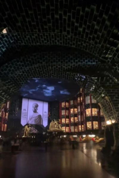 A grand, dark room with a large glowing portrait displayed on a screen.