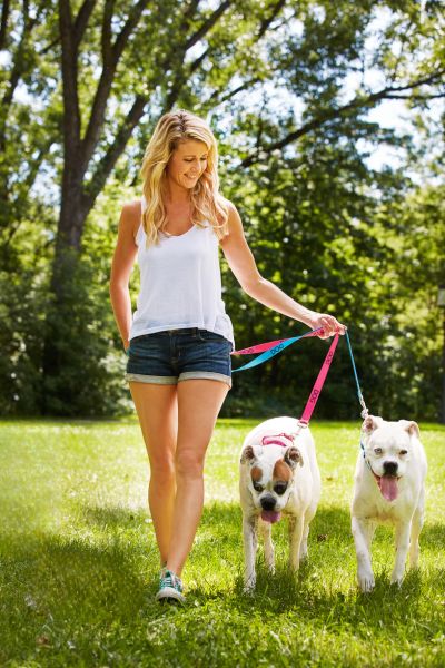 Young woman walking two dogs on a leashes