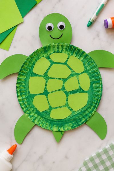 Paper plate turtle craft for kids made with green construction paper, painted shell pieces, googly eyes, and simple craft supplies.
